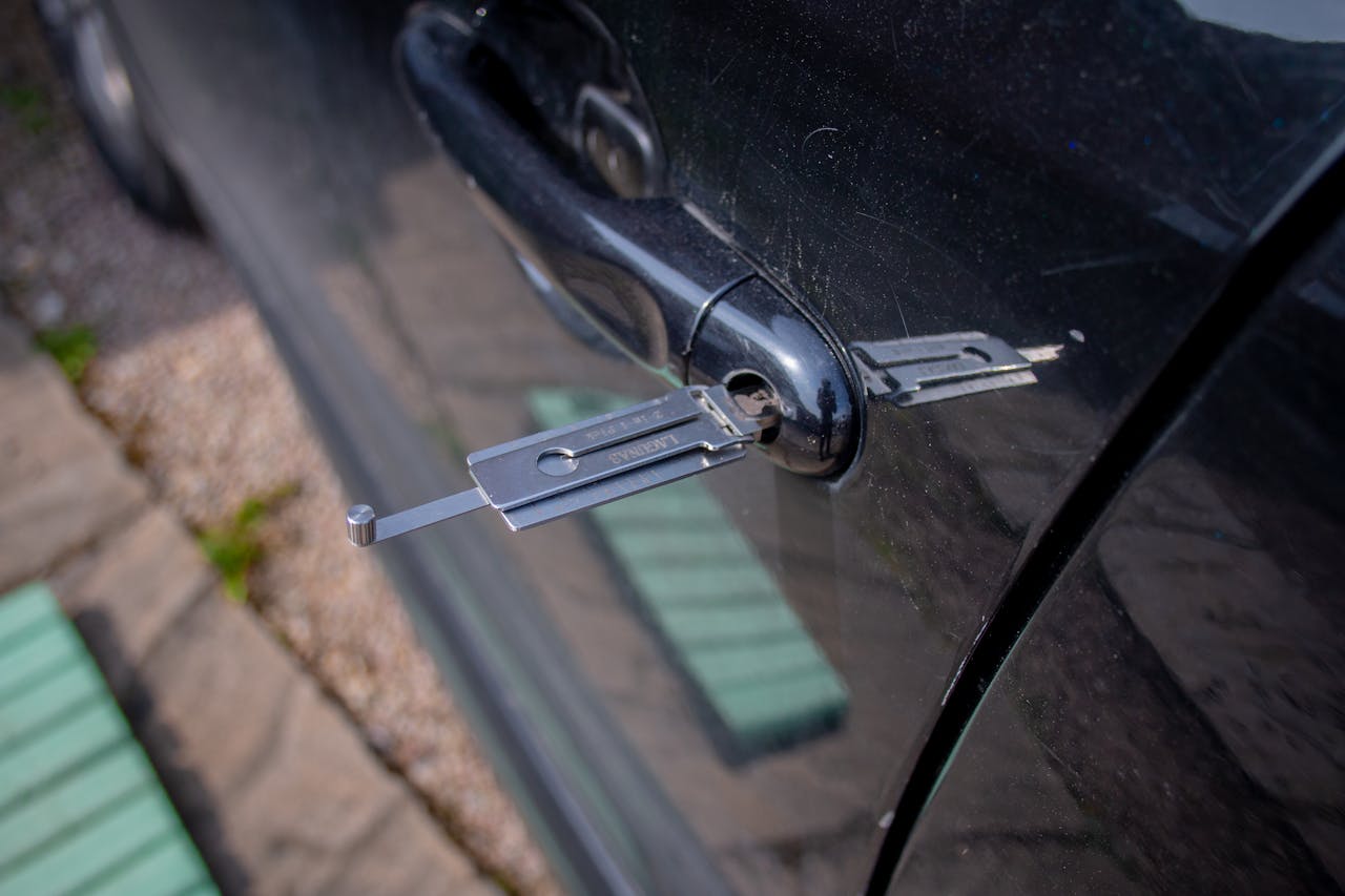 Services Close-up of a locksmith tool inserted into a car door lock, demonstrating security access.